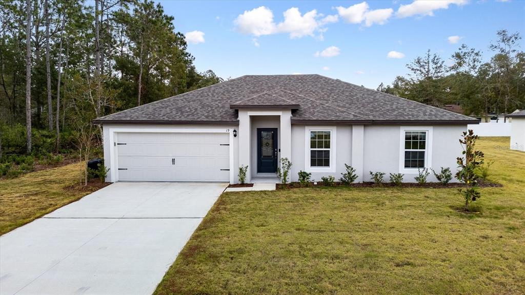 a front view of house with yard and trees in the background