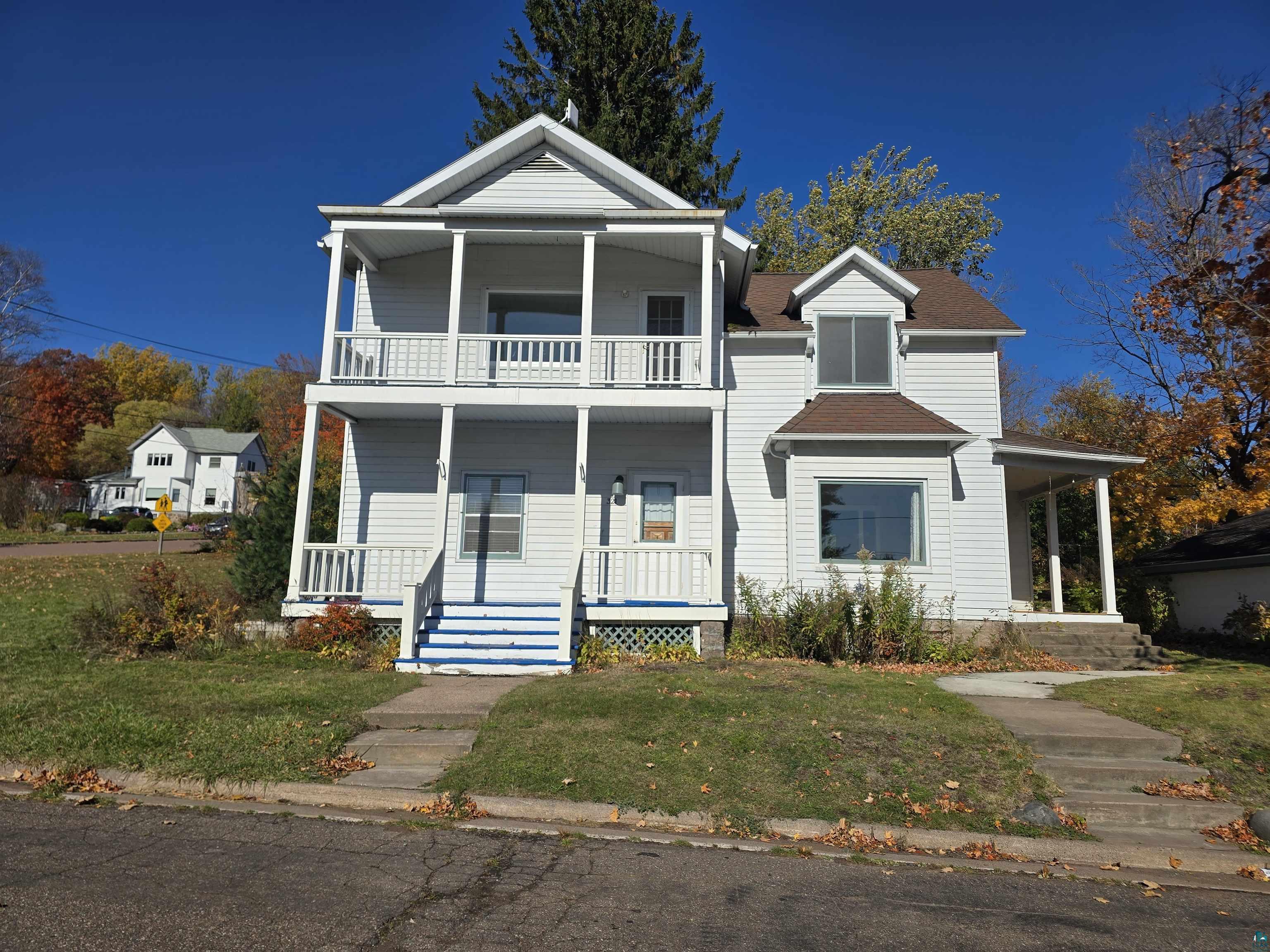 View of front facade featuring covered porch, a balcony, and a front lawn