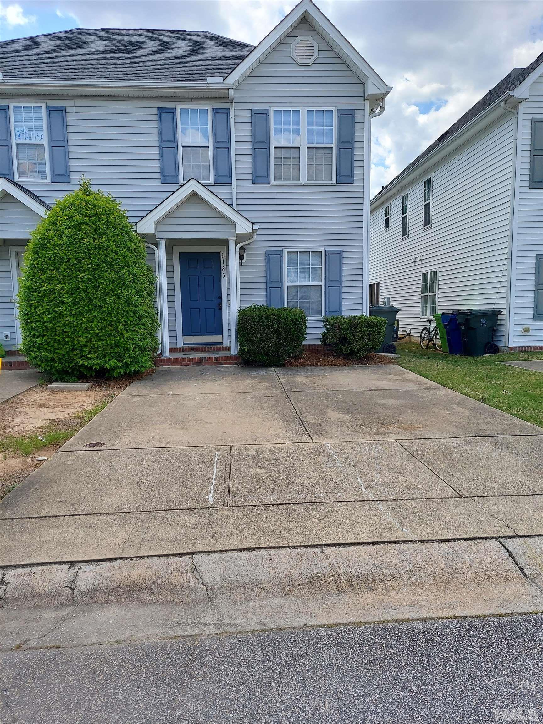 a front view of a house with yard and parking