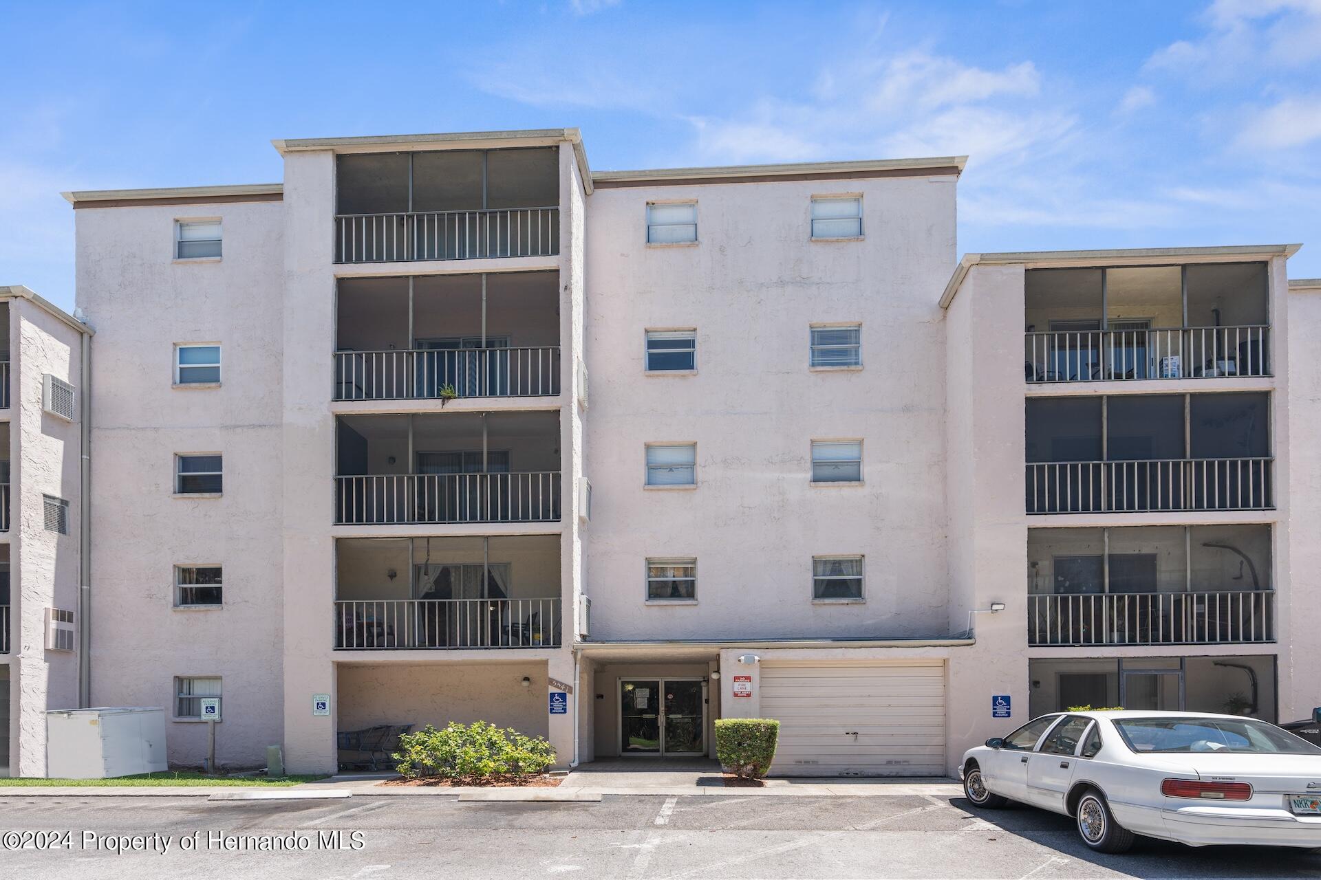 a front view of a building with a couple of cars parked in front of it