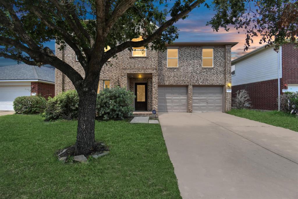 a front view of a house with a yard and tree