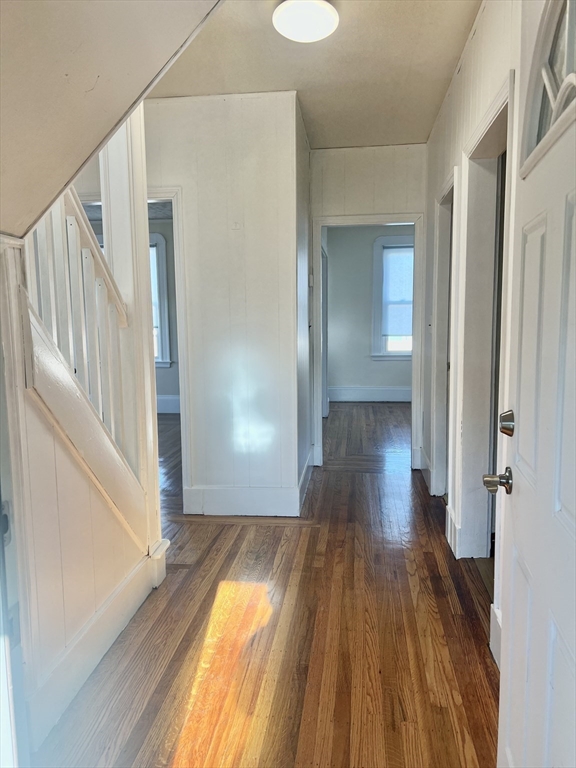 a view of a hallway with wooden floor and staircase