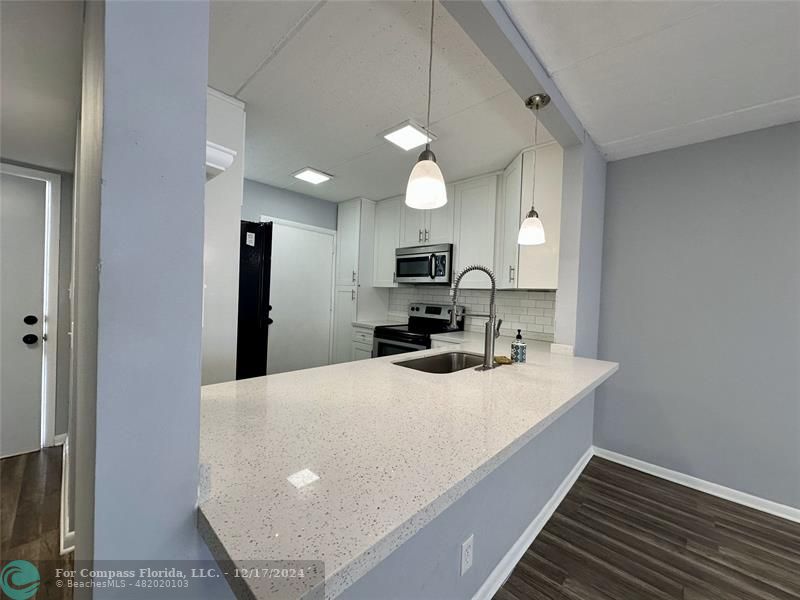 a kitchen with a sink a center island and stainless steel appliances