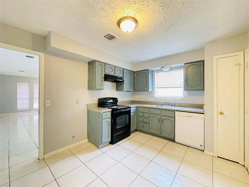 a kitchen with a sink a stove top oven and cabinetry