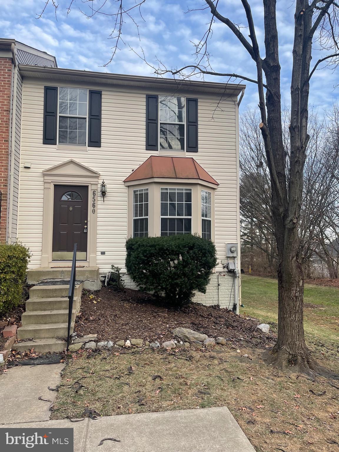 a view of a house with a yard and large tree