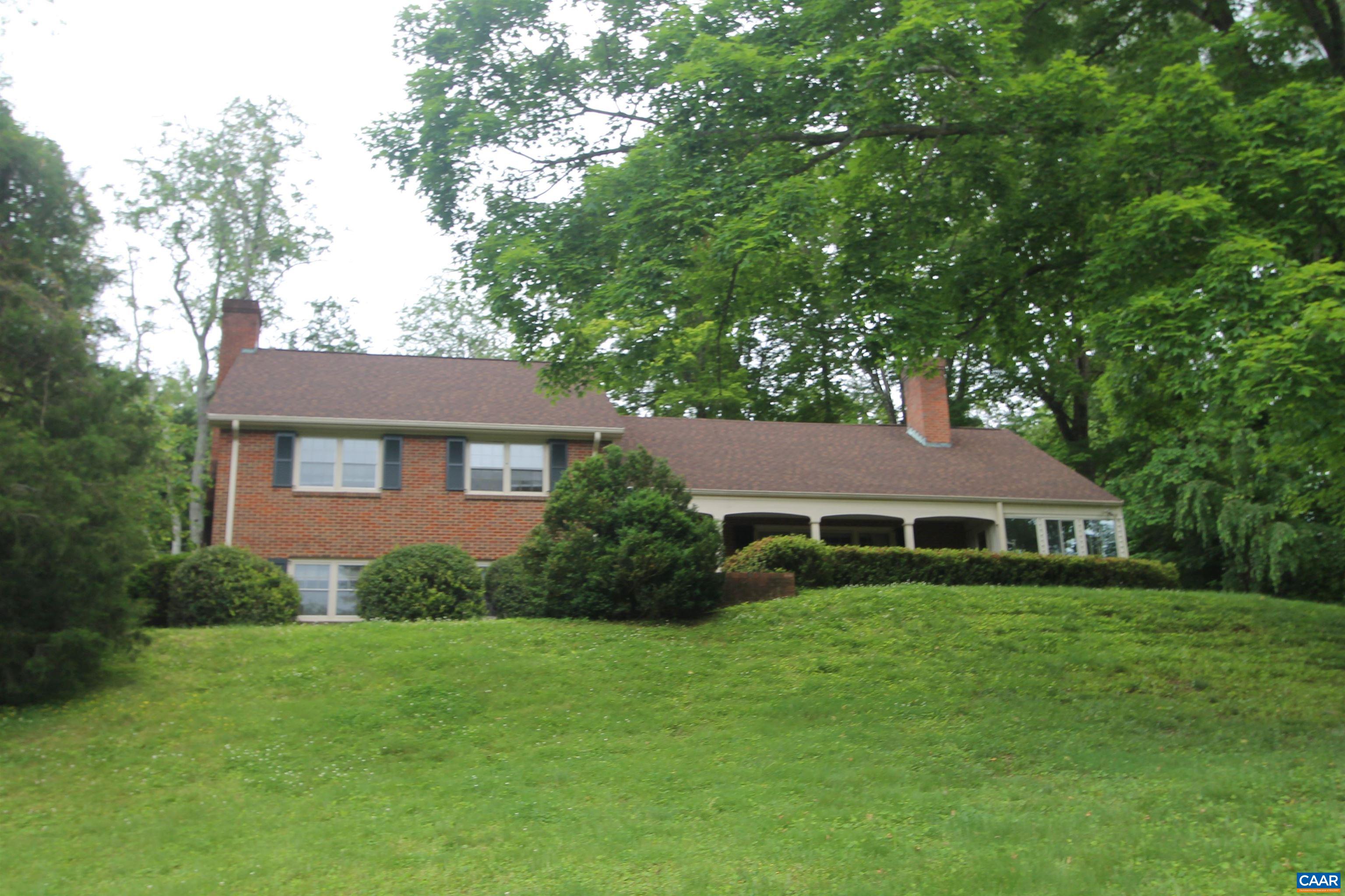 a view of a yard in front of a house with plants and large tree