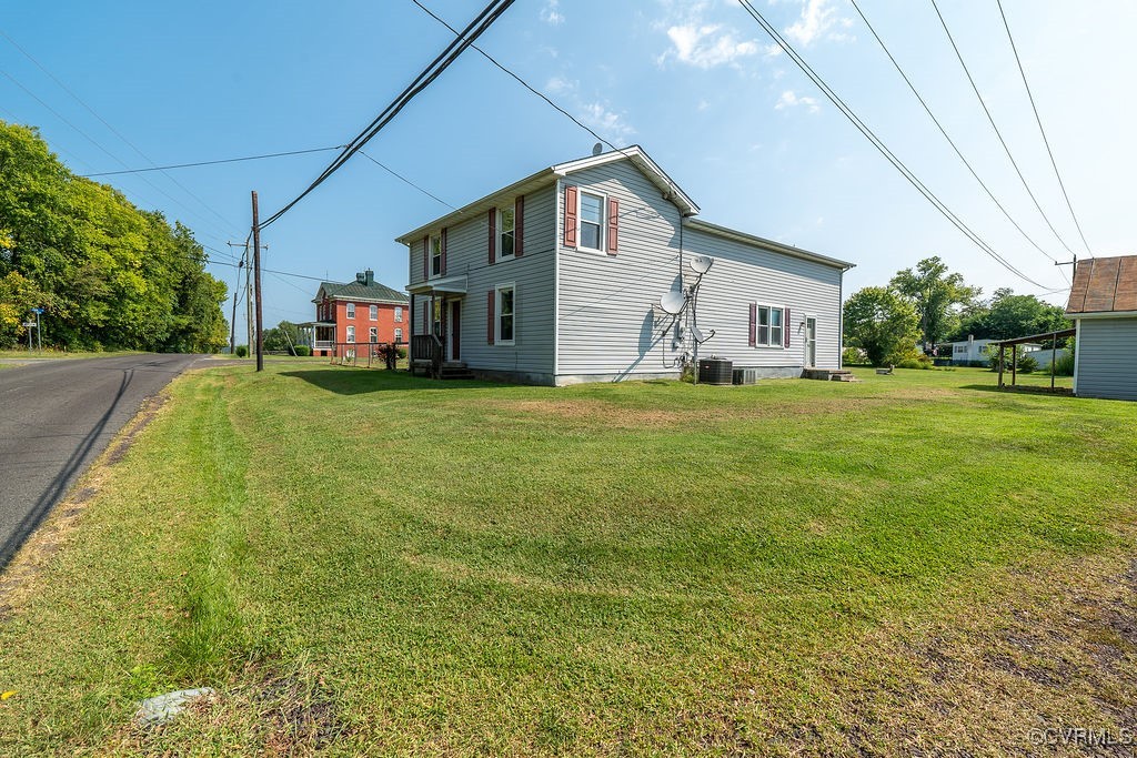 View of home's exterior with cooling unit and a ya