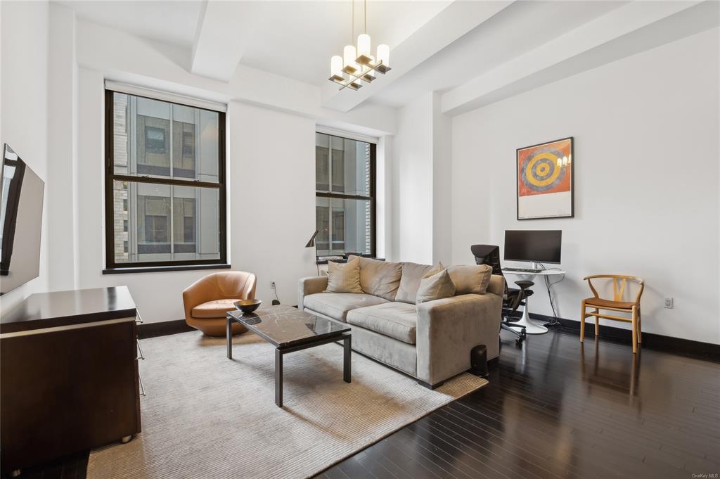 a living room with furniture two window and a flat screen tv