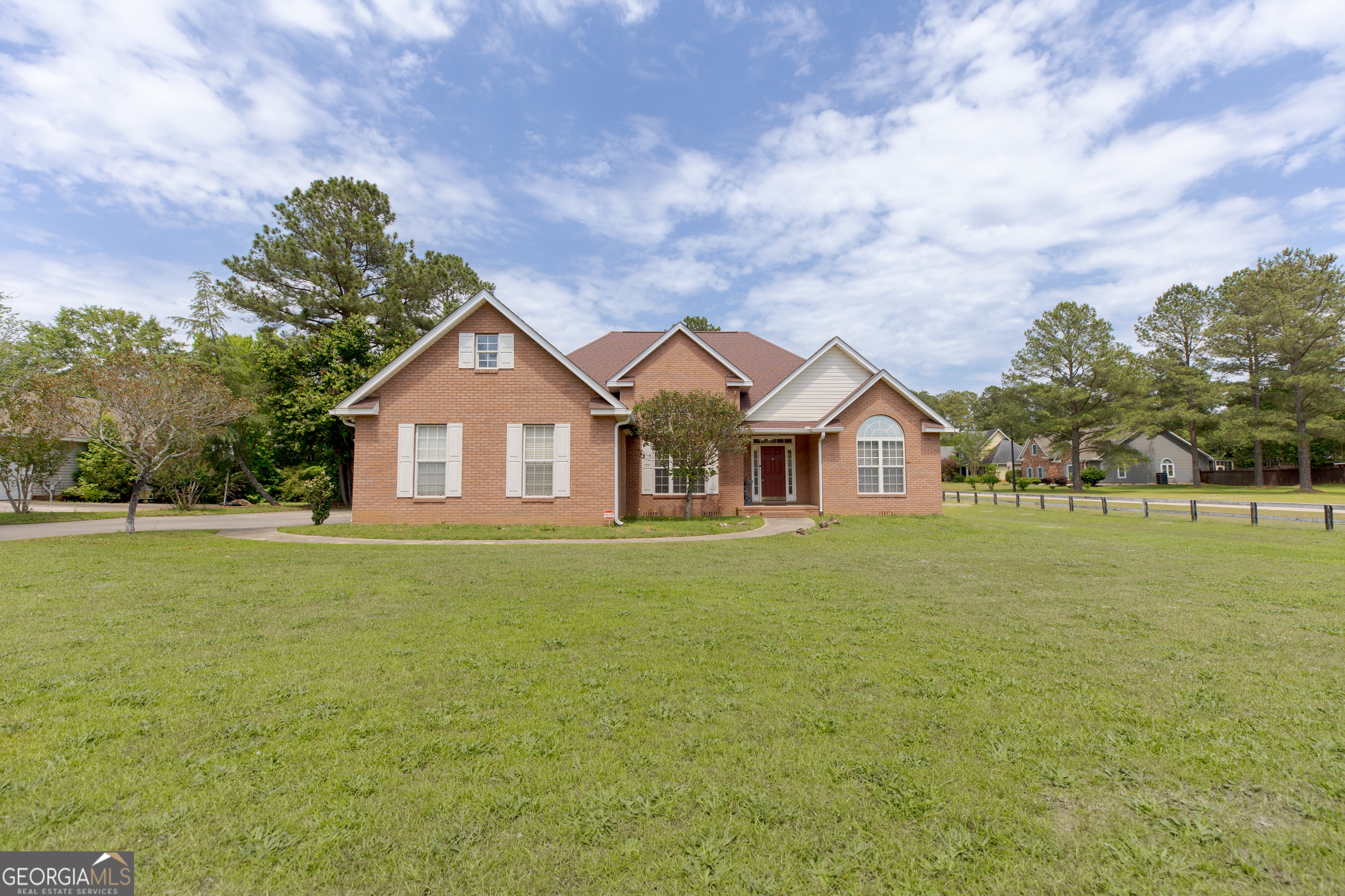 a view of a house with a big yard and large trees