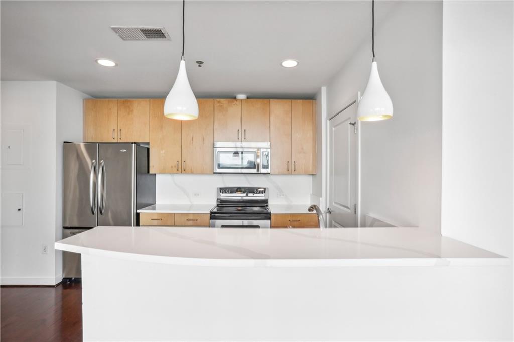 a kitchen with kitchen island a counter top space cabinets and stainless steel appliances