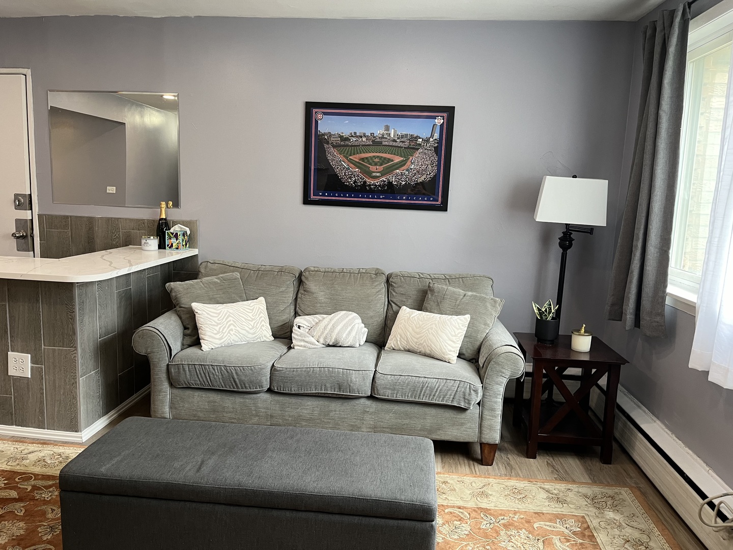 a living room with furniture and a large mirror next to a window