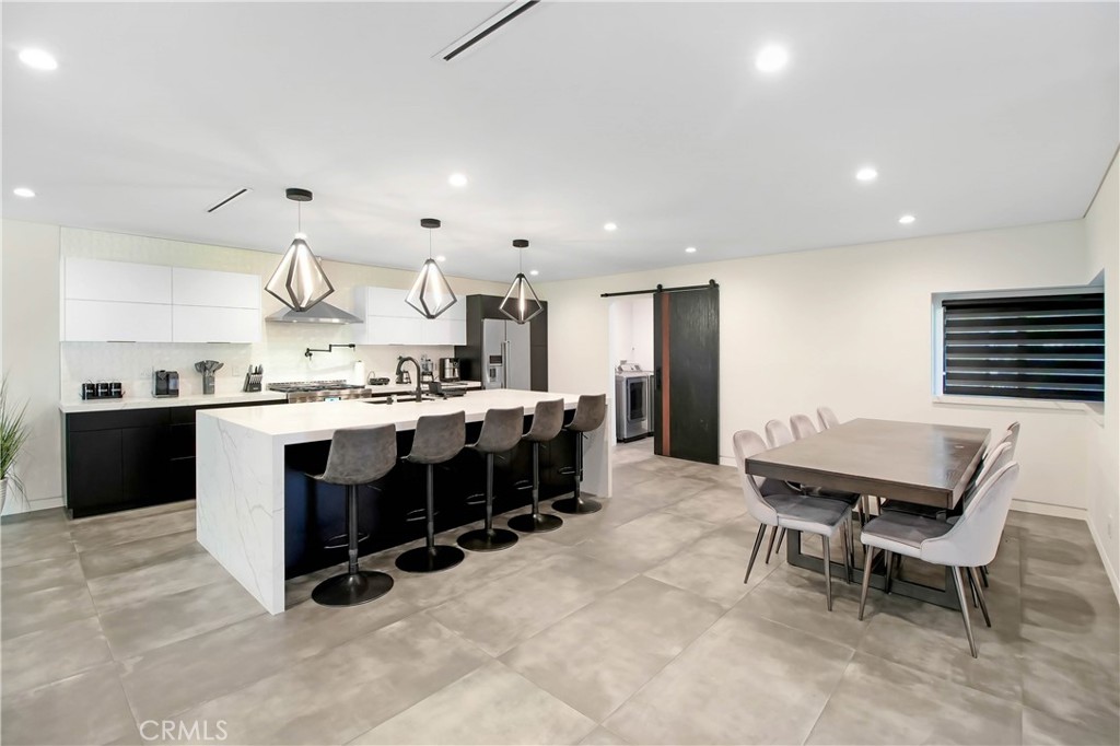 a kitchen with stainless steel appliances kitchen island granite countertop a table chairs sink and cabinets