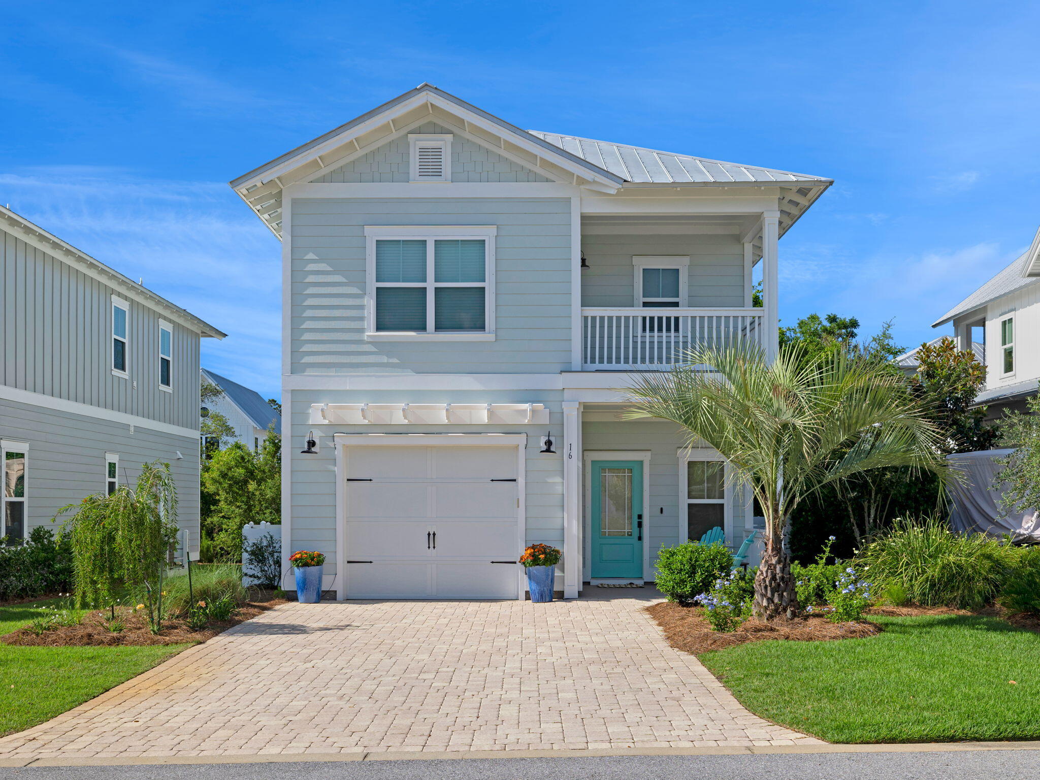 a front view of a house with a yard and potted plants