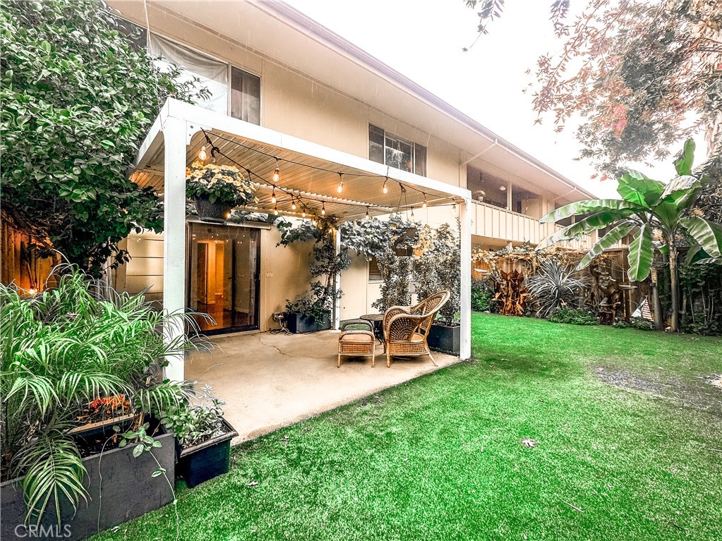 a view of a patio with table and chairs potted plants and large tree