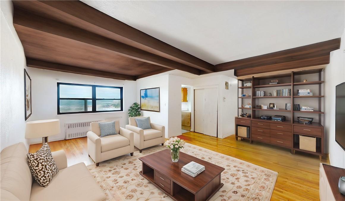 Living room with beamed ceiling, light hardwood / wood-style flooring, and radiator heating unit