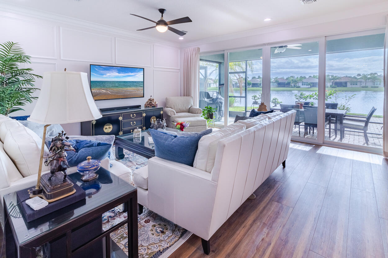 a living room with furniture floor to ceiling window and wooden floor