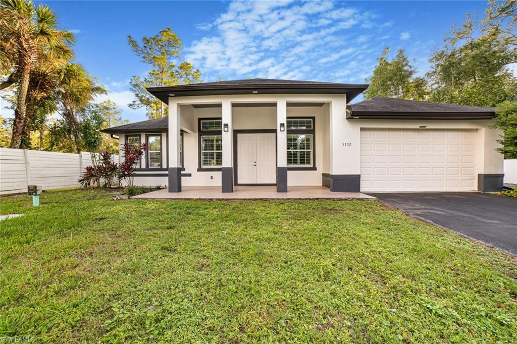 View of front of house with covered porch, a garage, and a front yard