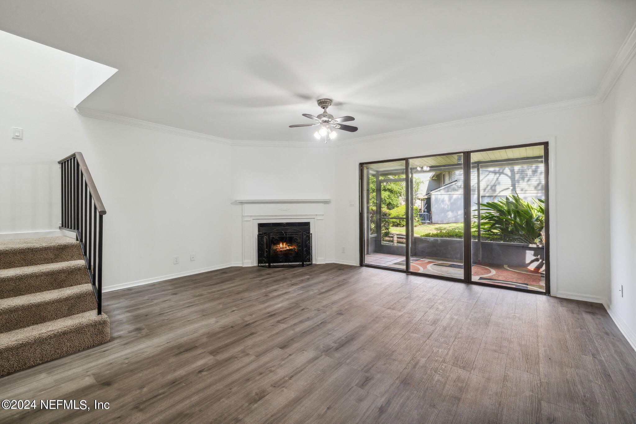 a view of an empty room with wooden floor and a fireplace