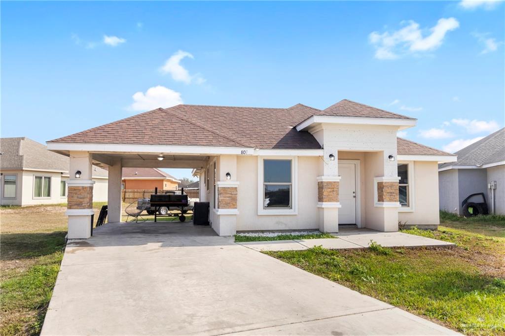 View of front facade featuring a front lawn and a carport