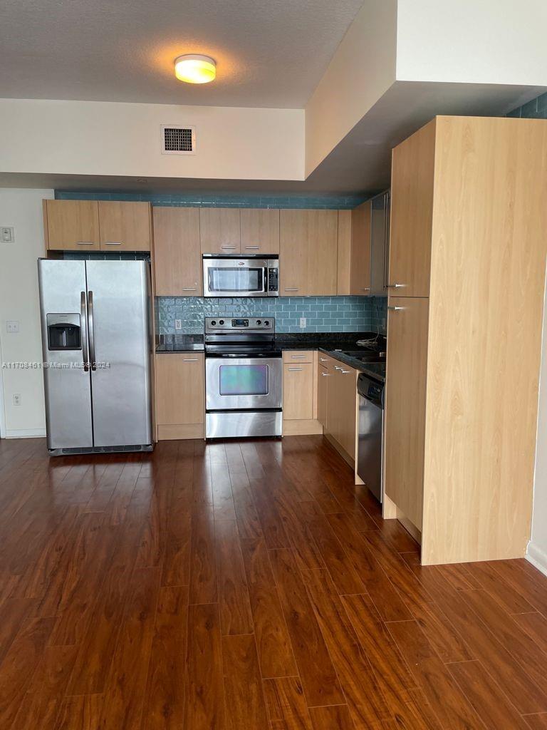 a kitchen with stainless steel appliances a refrigerator and wooden floor