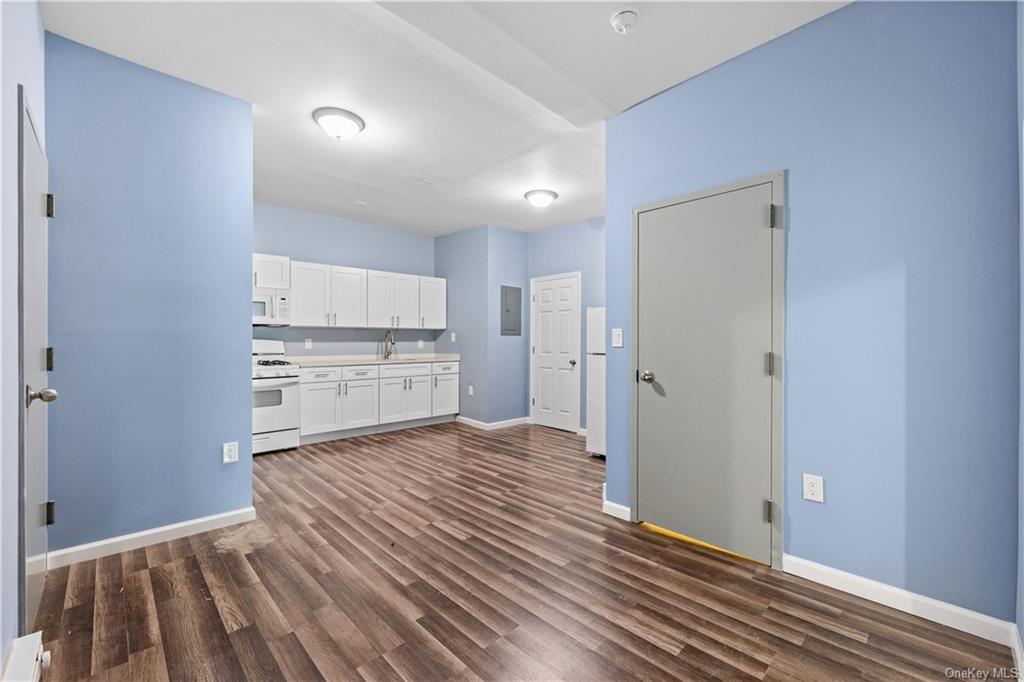 Kitchen featuring white appliances, dark wood-type flooring, sink, and white cabinets