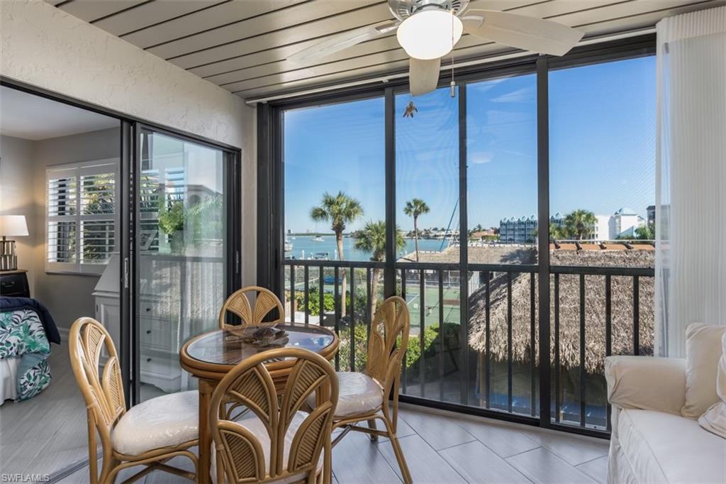 Sunroom / solarium featuring ceiling fan and a water view