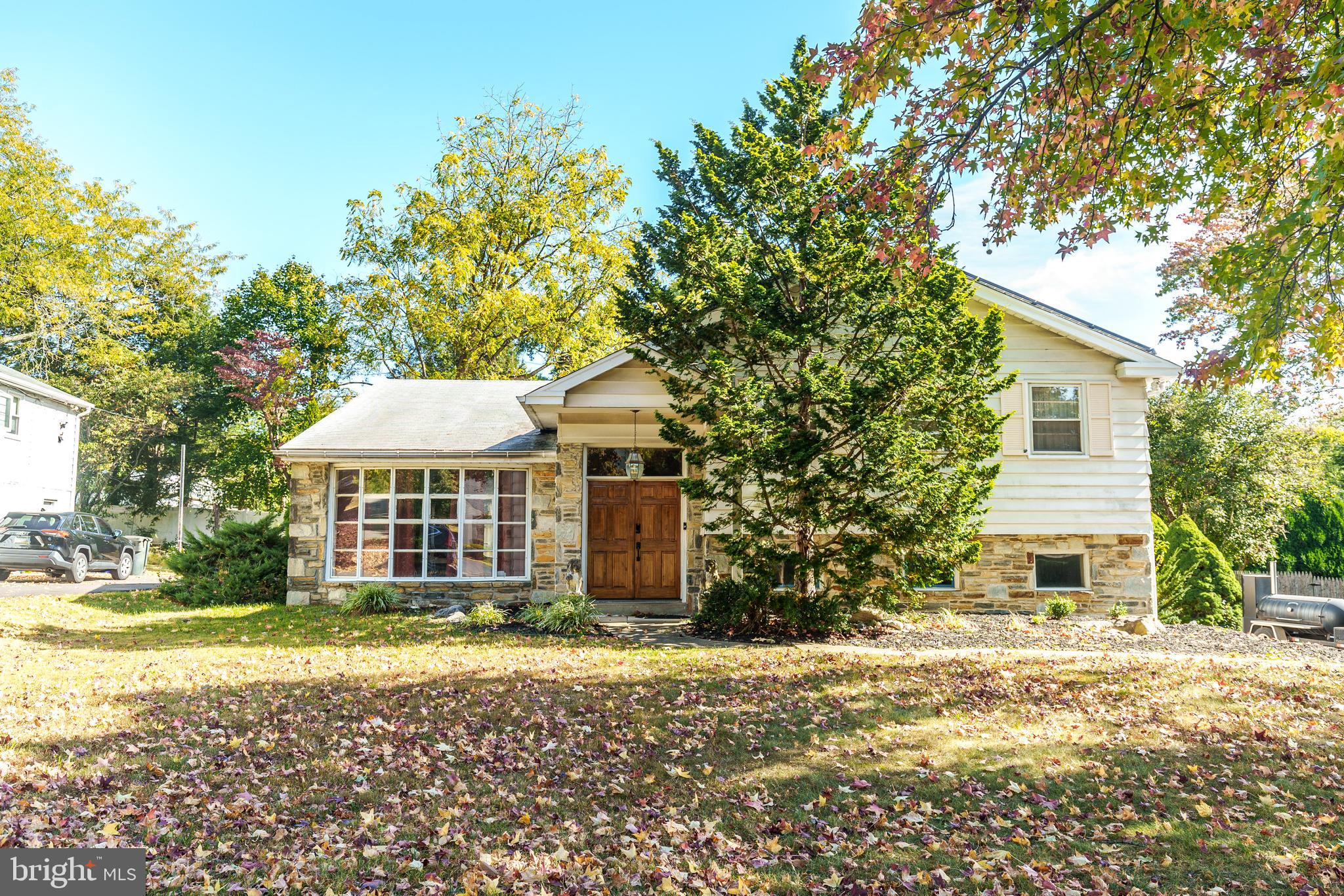 a front view of a house with a garden and trees