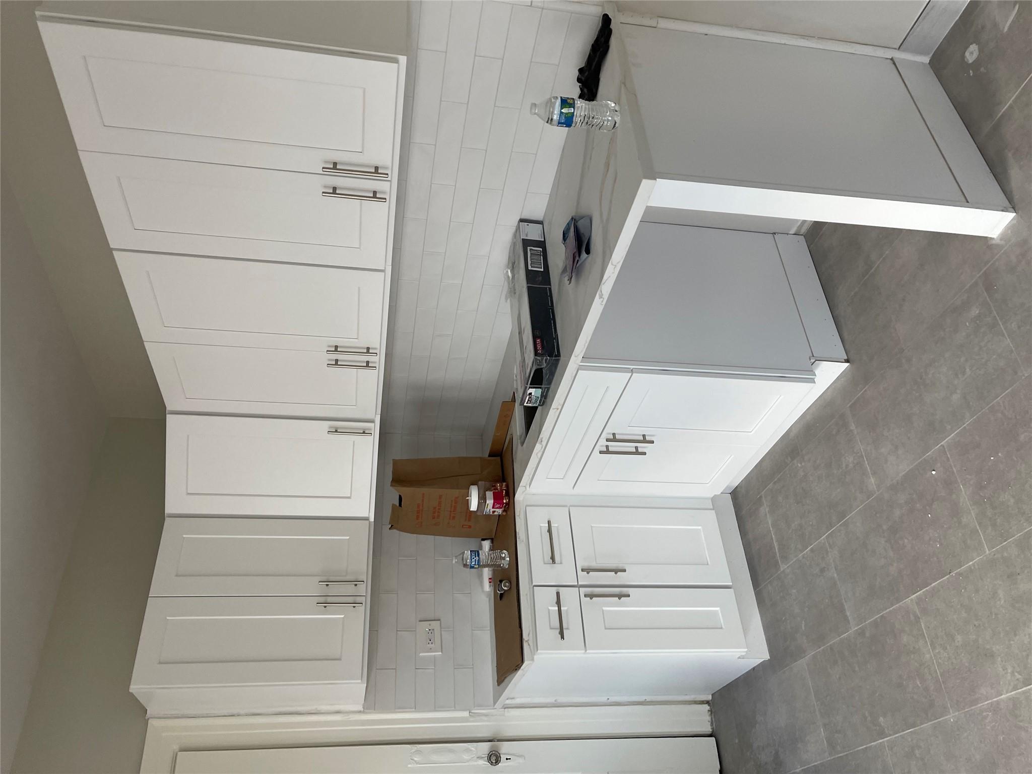 Kitchen featuring decorative backsplash and white cabinetry