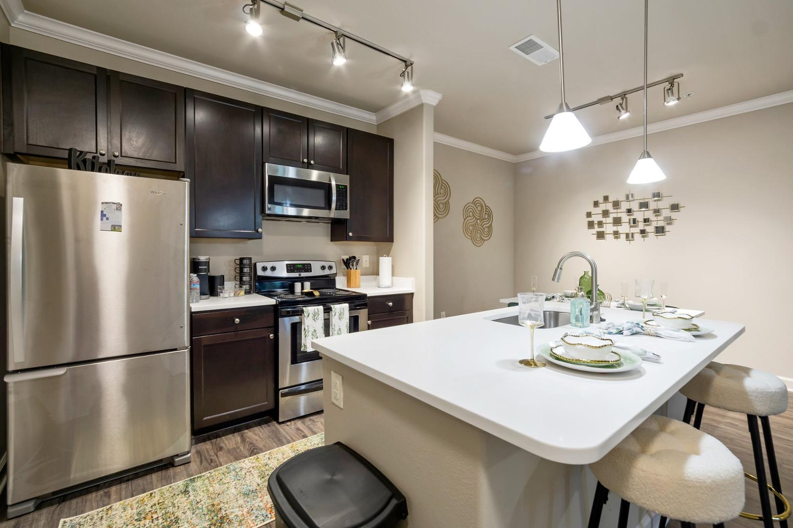 a kitchen with a refrigerator a stove a sink and chairs