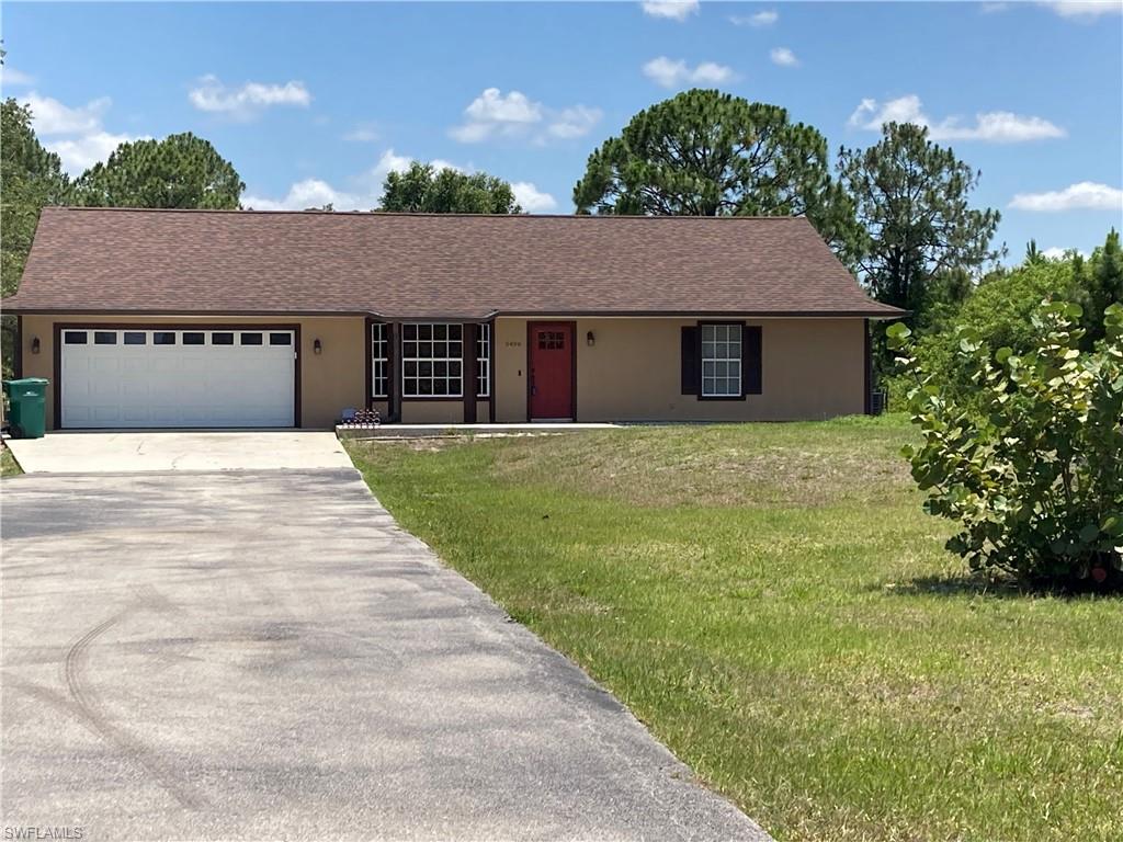 a front view of house with yard and trees in the background