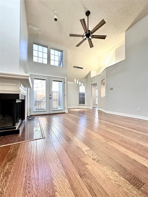 a view of a livingroom with wooden floor a ceiling fan and windows