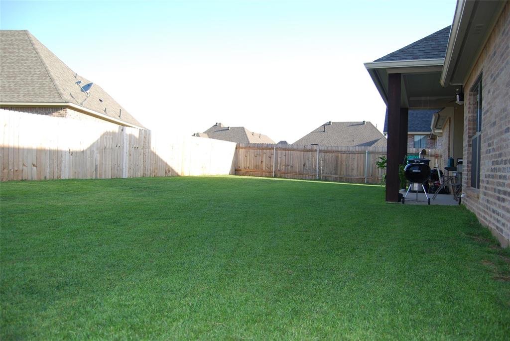 a view of backyard with barbeque grill and wooden fence