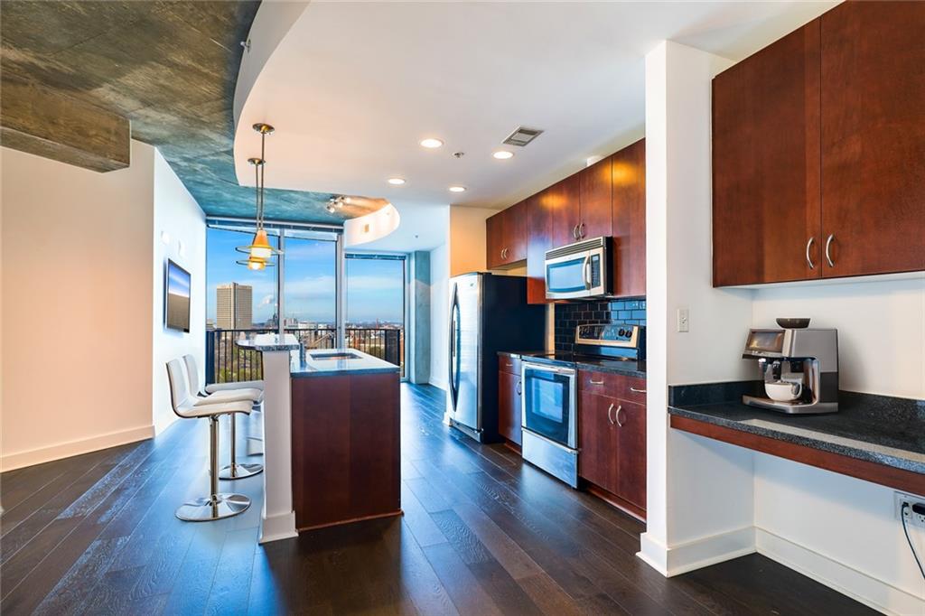 a open kitchen with stainless steel appliances granite countertop a refrigerator stove and wooden floor