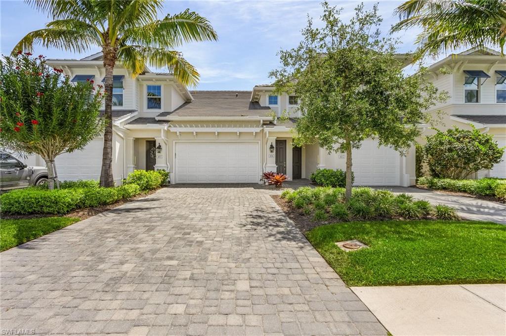 a front view of a house with a garden and palm trees