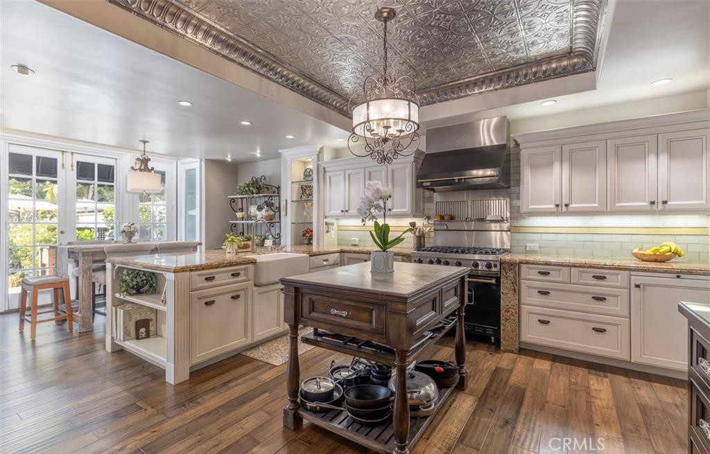 a kitchen with stainless steel appliances granite countertop a sink a stove and a wooden floors