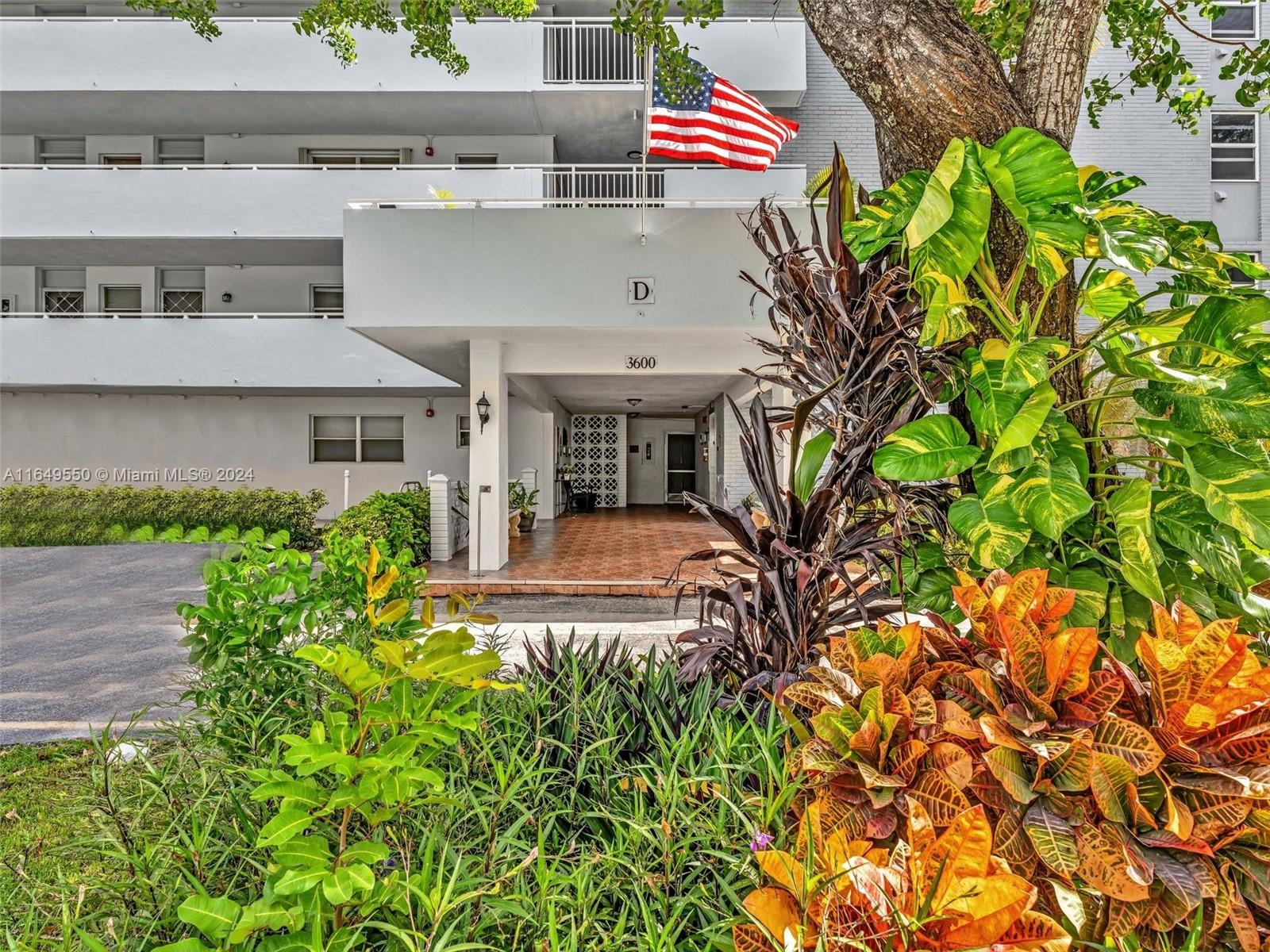 a front view of white house with a yard and plants