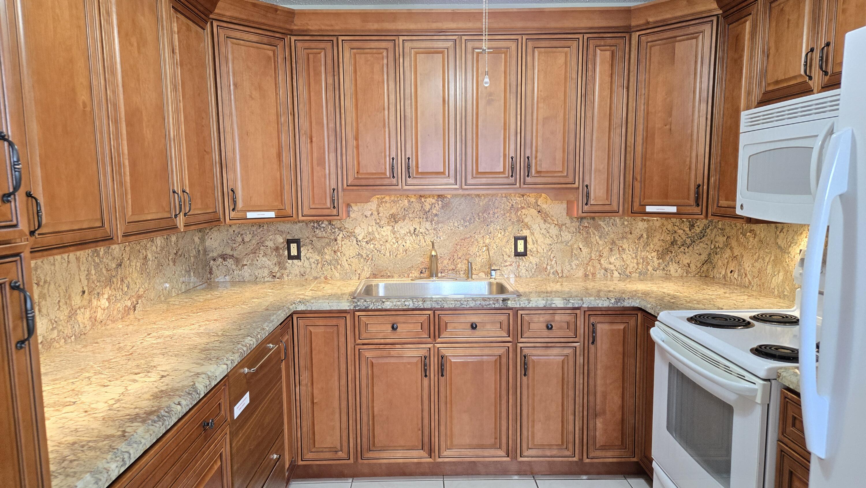 a kitchen with granite countertop a sink a stove and cabinets