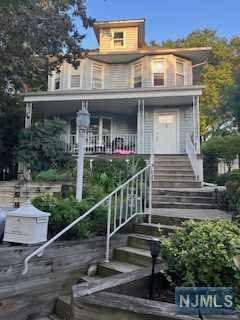 a view of a house with entrance stairs and a garden