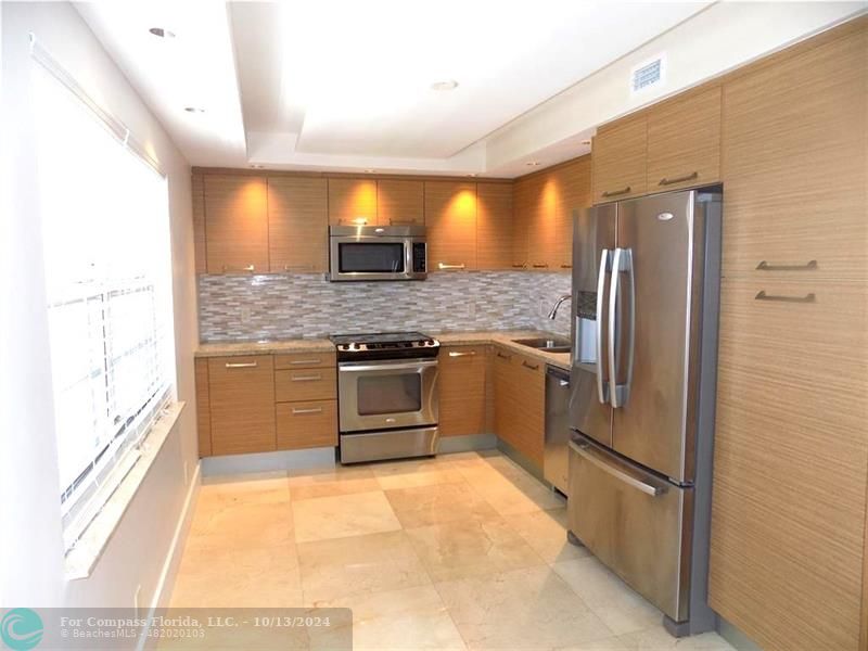 a kitchen with stainless steel appliances granite countertop a refrigerator and a sink