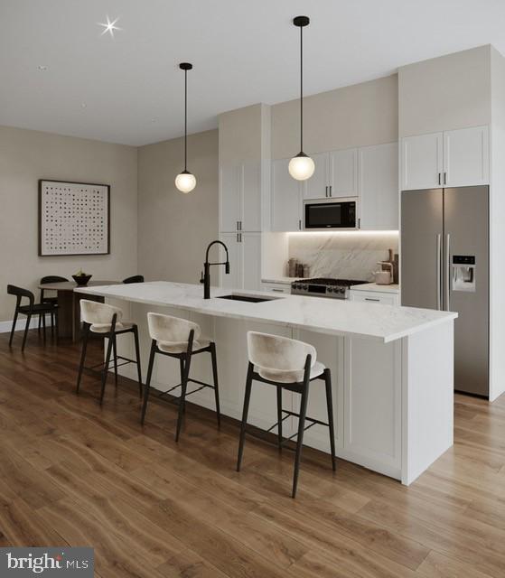 a kitchen with stainless steel appliances granite countertop a dining table chairs and a refrigerator