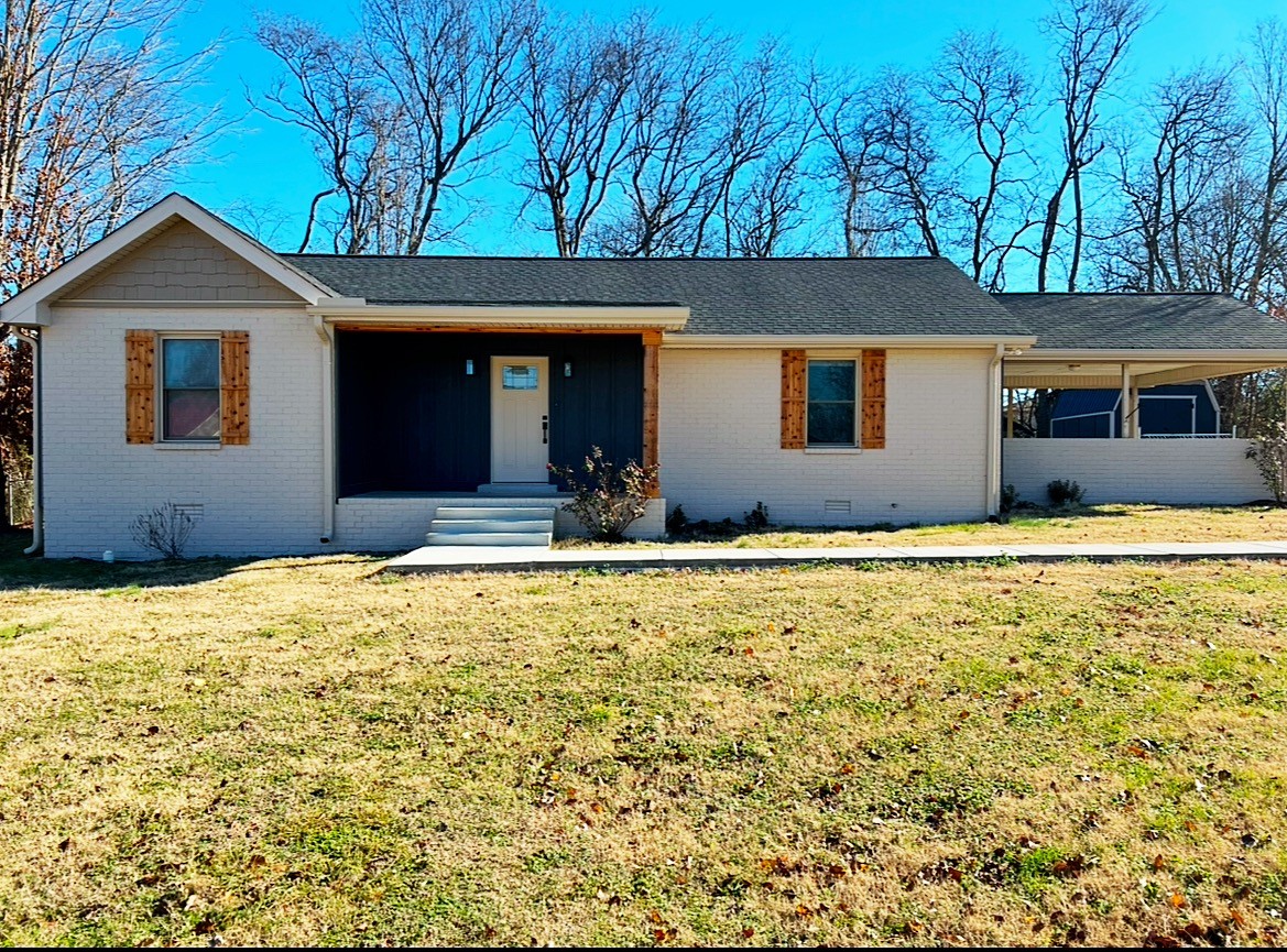 a front view of house with yard and trees in the background