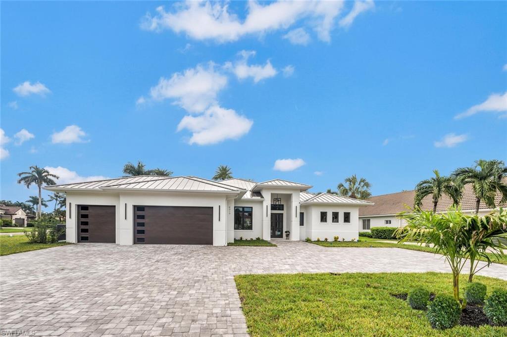 Stunning frontal view  of home with 3 car garage and oversized circular driveway with  brick pavers