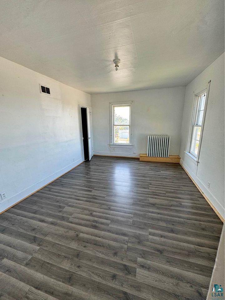 Empty room featuring radiator heating unit and dark hardwood / wood-style floors