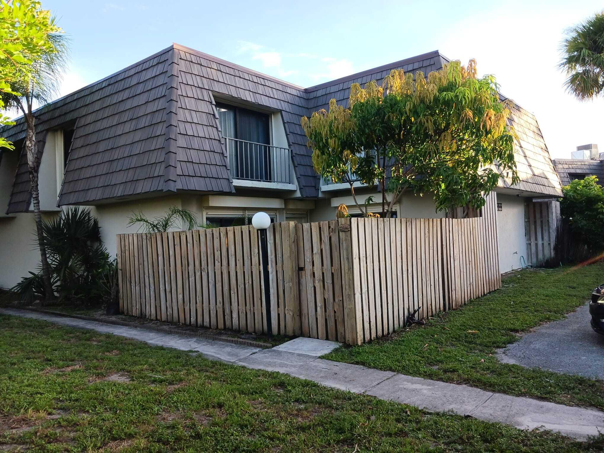 a small barn in front of a house with wooden fence