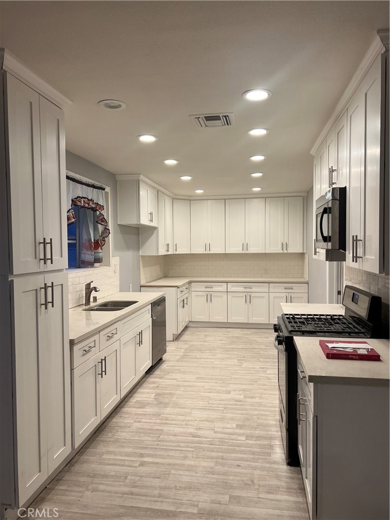 a large kitchen with stainless steel appliances granite countertop a stove and a sink