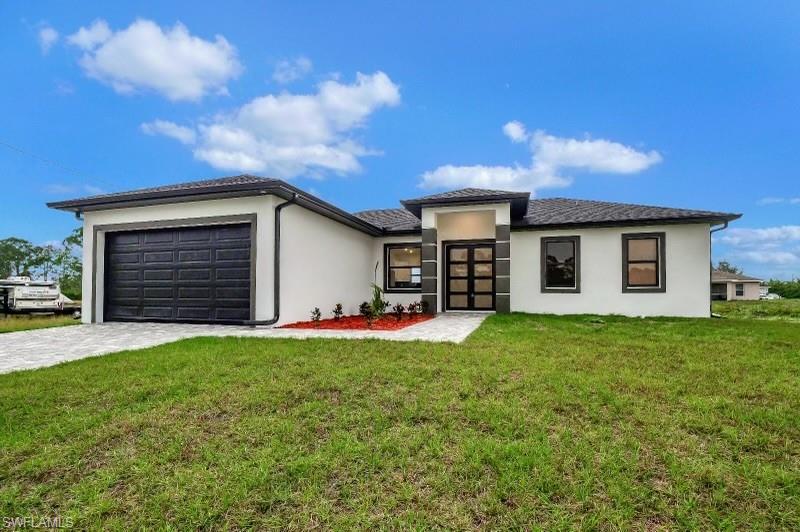 View of front of property with a garage and a front lawn