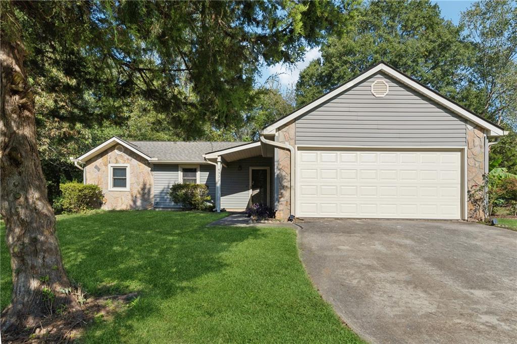 a front view of house with yard and trees in the background