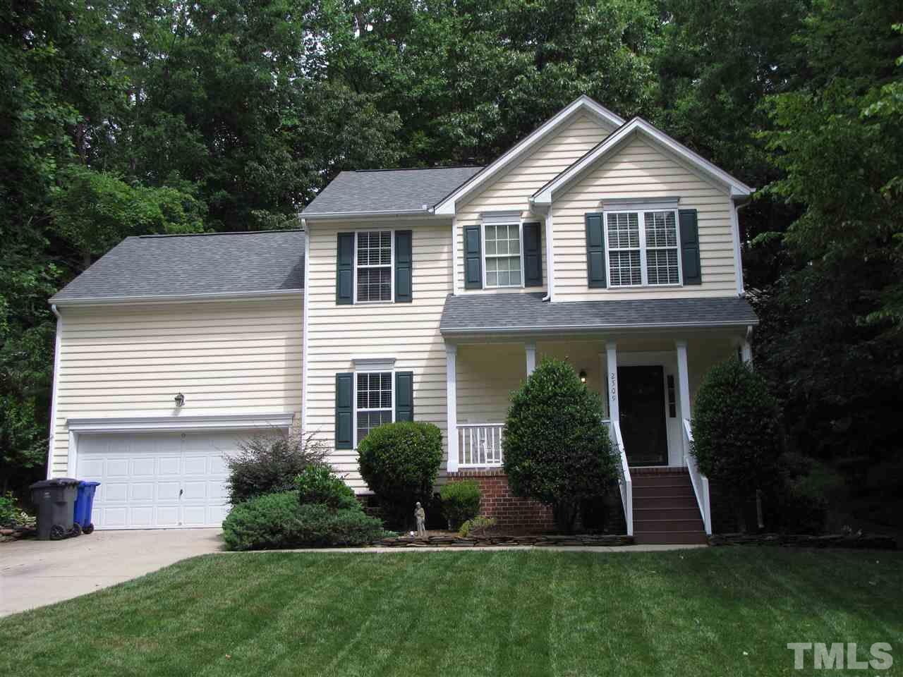 a front view of a house with a yard and green space