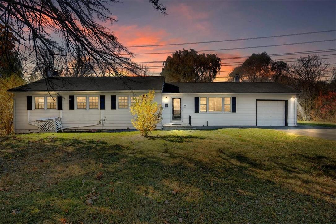 Ranch-style house featuring a lawn and a garage.