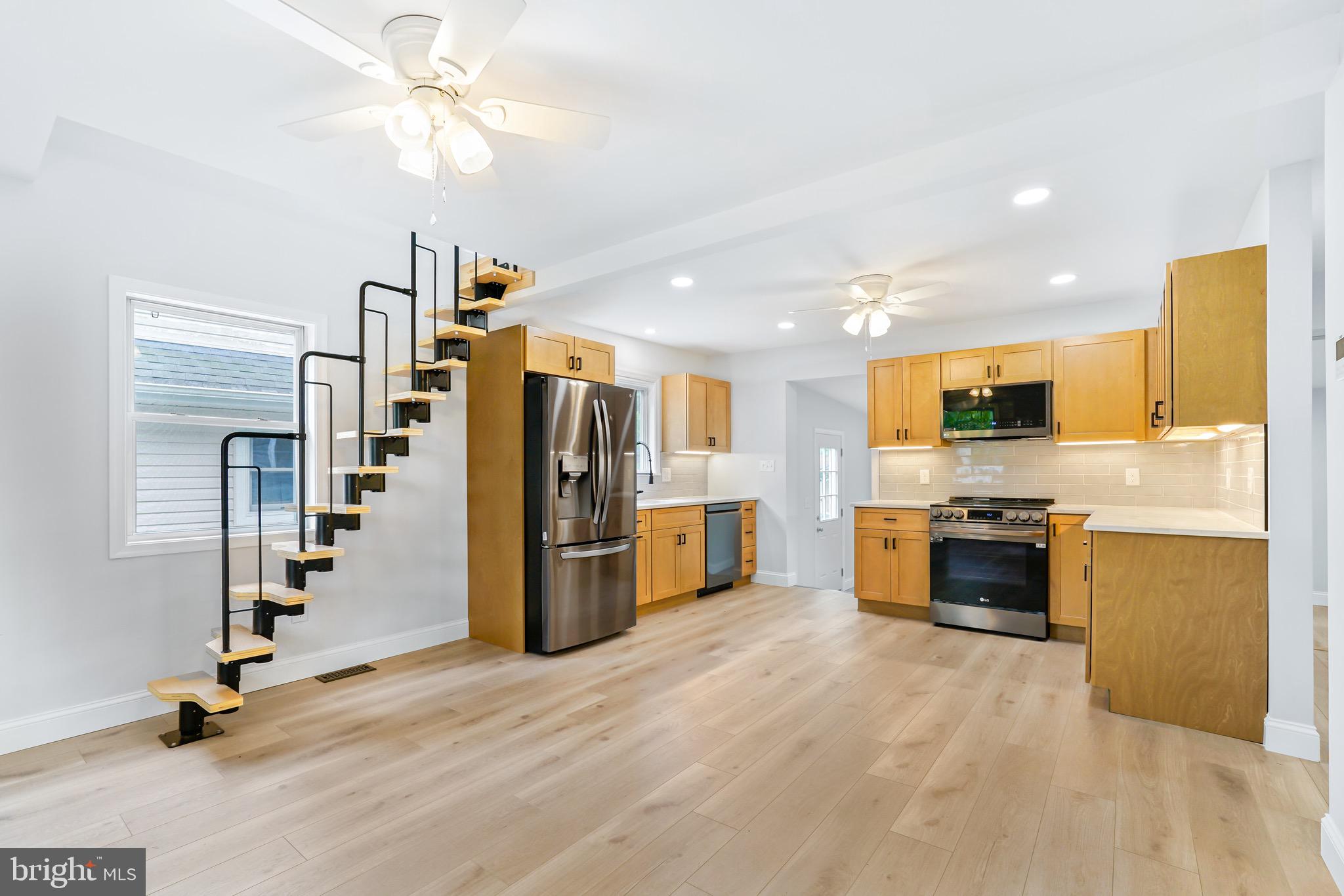 a view of kitchen with stainless steel appliances kitchen island wooden floor and living room